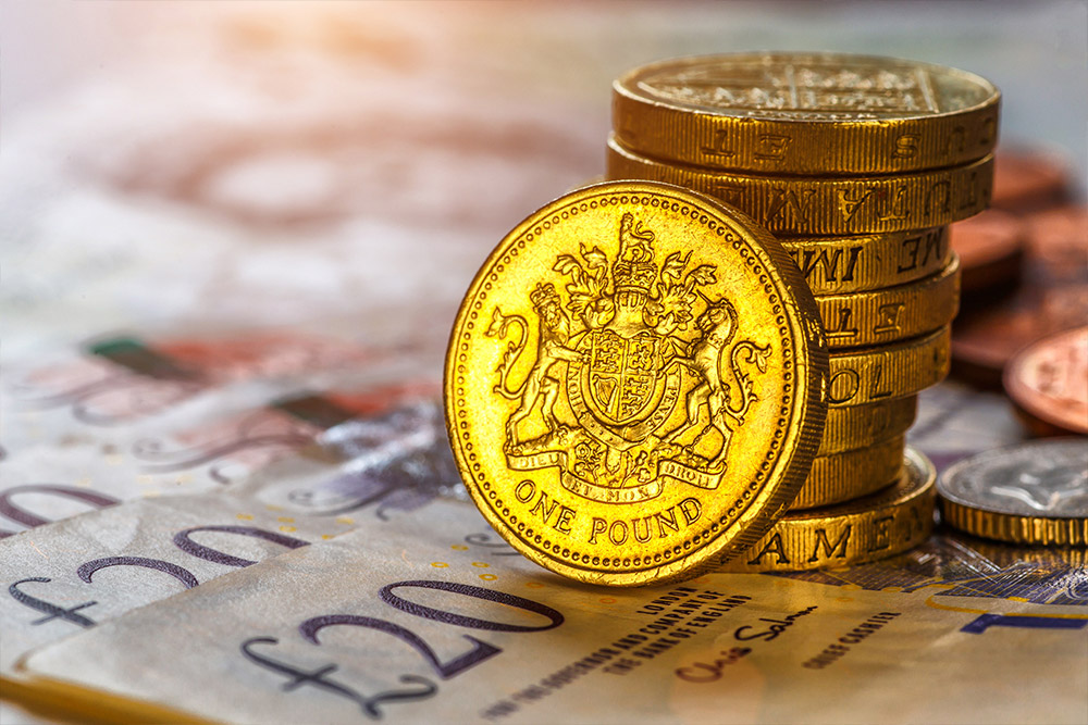 A stack British one pound coins sits on top of a pile of £20 notes, earned with Amazon arbitrage software.