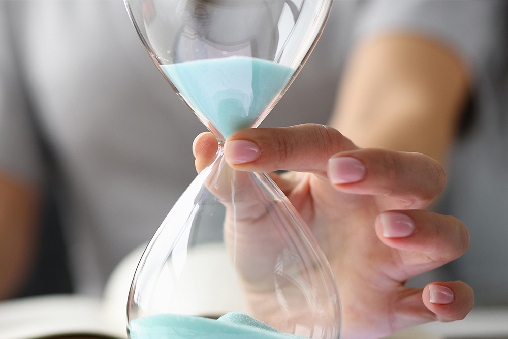 A woman holds an hourglass as sand pours through the glass illustrating how Amazon arbitrage software by Profit Runner can save you time.