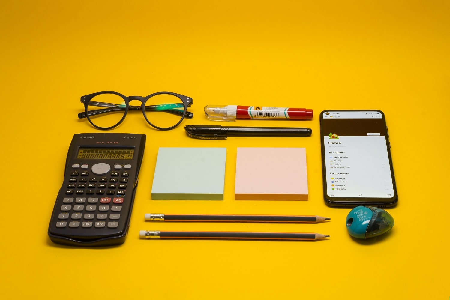 A calculator, notepad, pencils and a pair of reading glasses, tools used to help calculate Amazon return on investment.