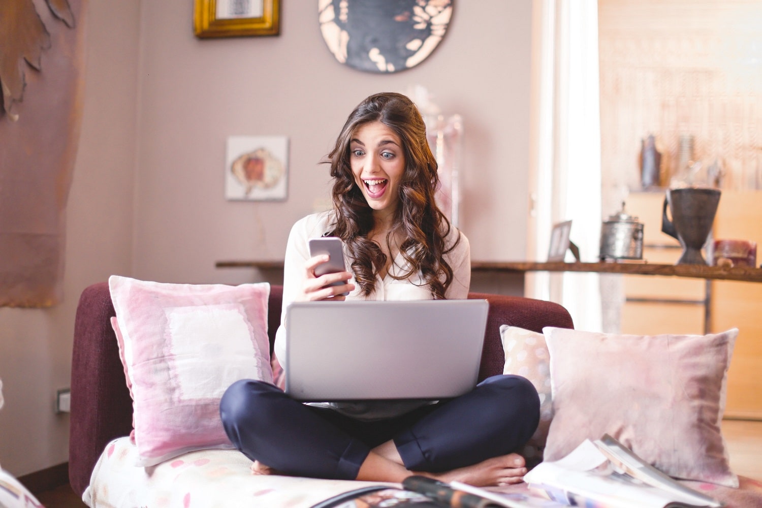 Happy woman on a sofa, using her laptop to sell products on Amazon.