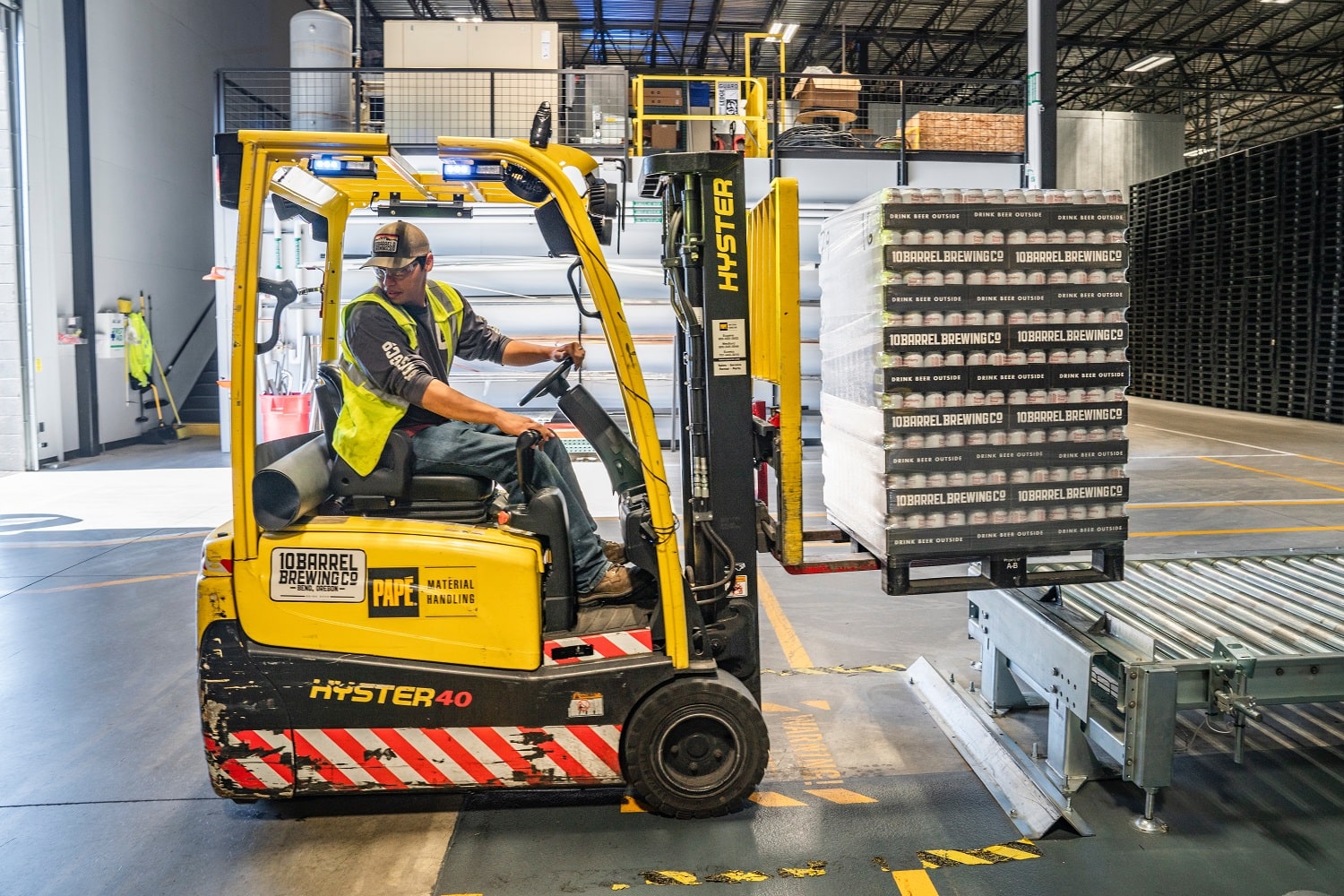 A man driving a forklift in an Amazon wholesale warehouse.