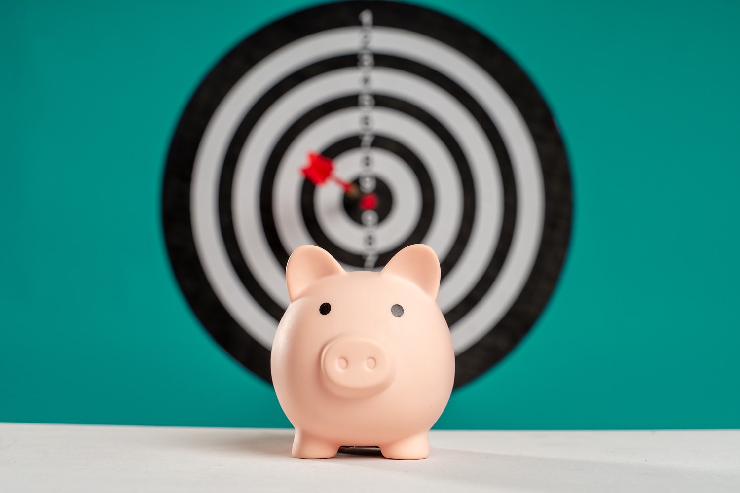 A piggy bank with a target in the background, representing an investment budget for Amazon sellers starting up a business.